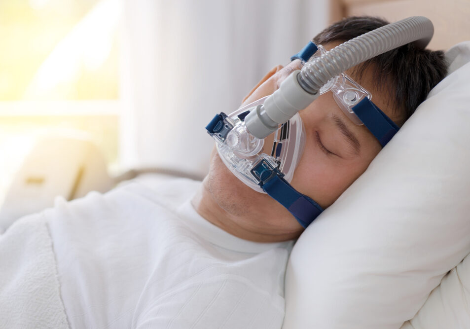 Patiënt met slaapapneu in bed met zuurstof masker op.