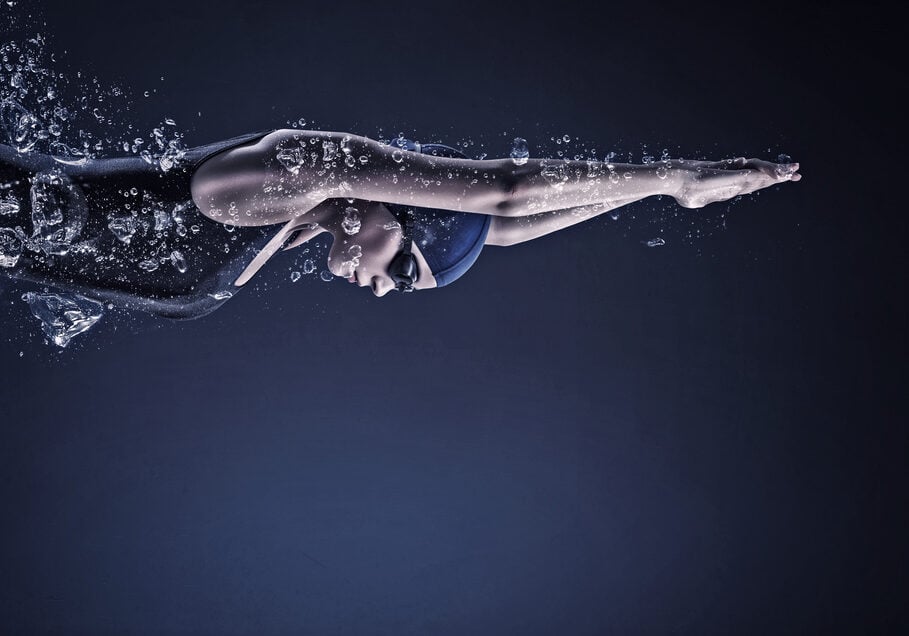 Wedstrijd zwemster met stevige schouderpartij, na duik onderwater.