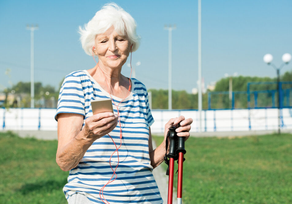 Vrouw houdt haar vorderingen met nordic walking bij op smartphone.