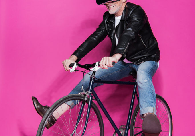Oudere man met VR-bril op fiets.