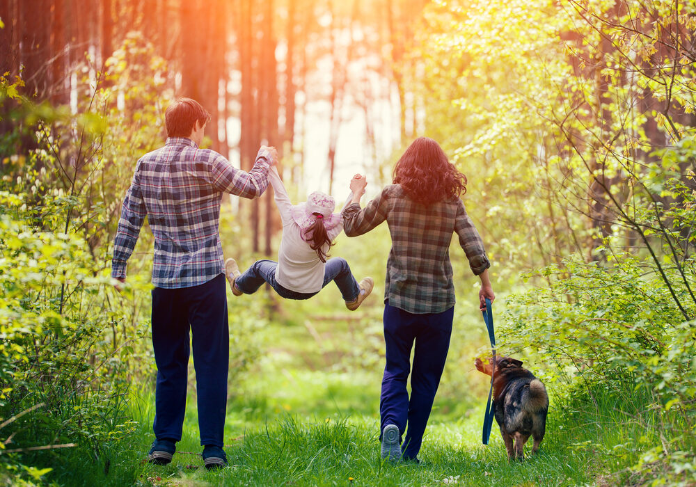 Ouders die speels hun kind 'slinger' tijdens zondagswandeling.