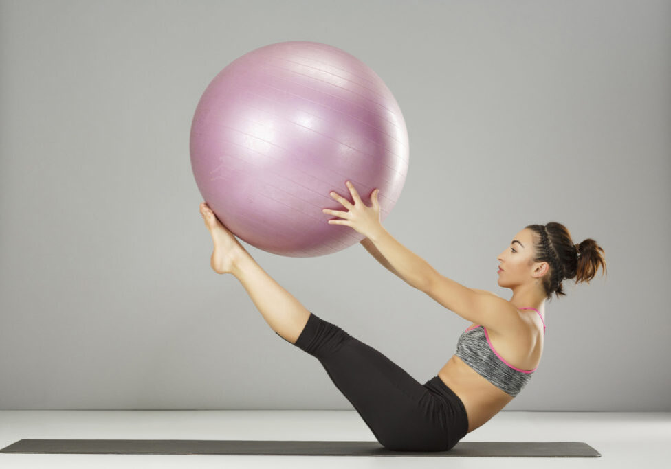 Fitness ball. Pilates stretching  training.  Athletic young woman practicing advanced sports training, on a fitness ball. Yoga wheel poses. Gymnastics exercise.  Fitness health club.