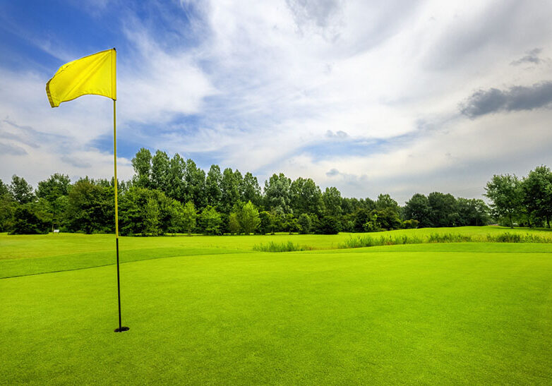 golf course with yellow flag on 18th hole at cloudy sky