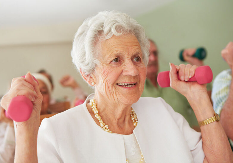 An elderly lady lifting light weights to strengthen her arm muscles