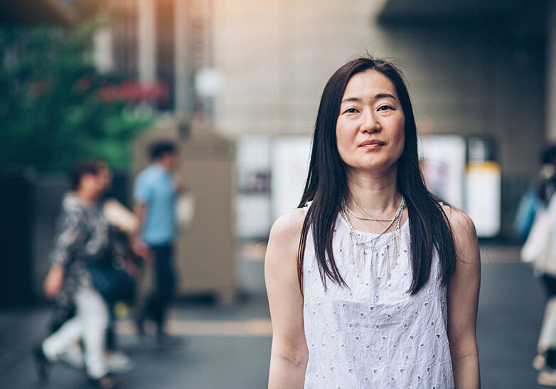 Portrait of a middle aged Japanese woman standing outdoors with arms crossed